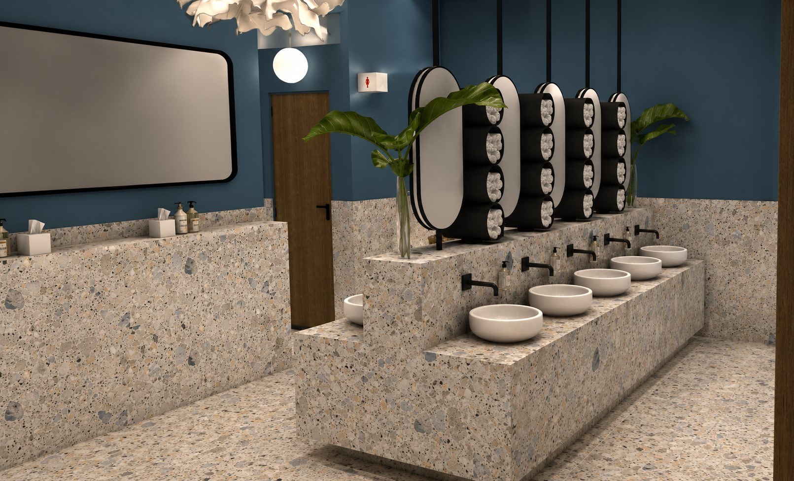 A TBRC restroom interior: terrazzo surfaces, deep teal walls, round mirrors and warm brass fittings